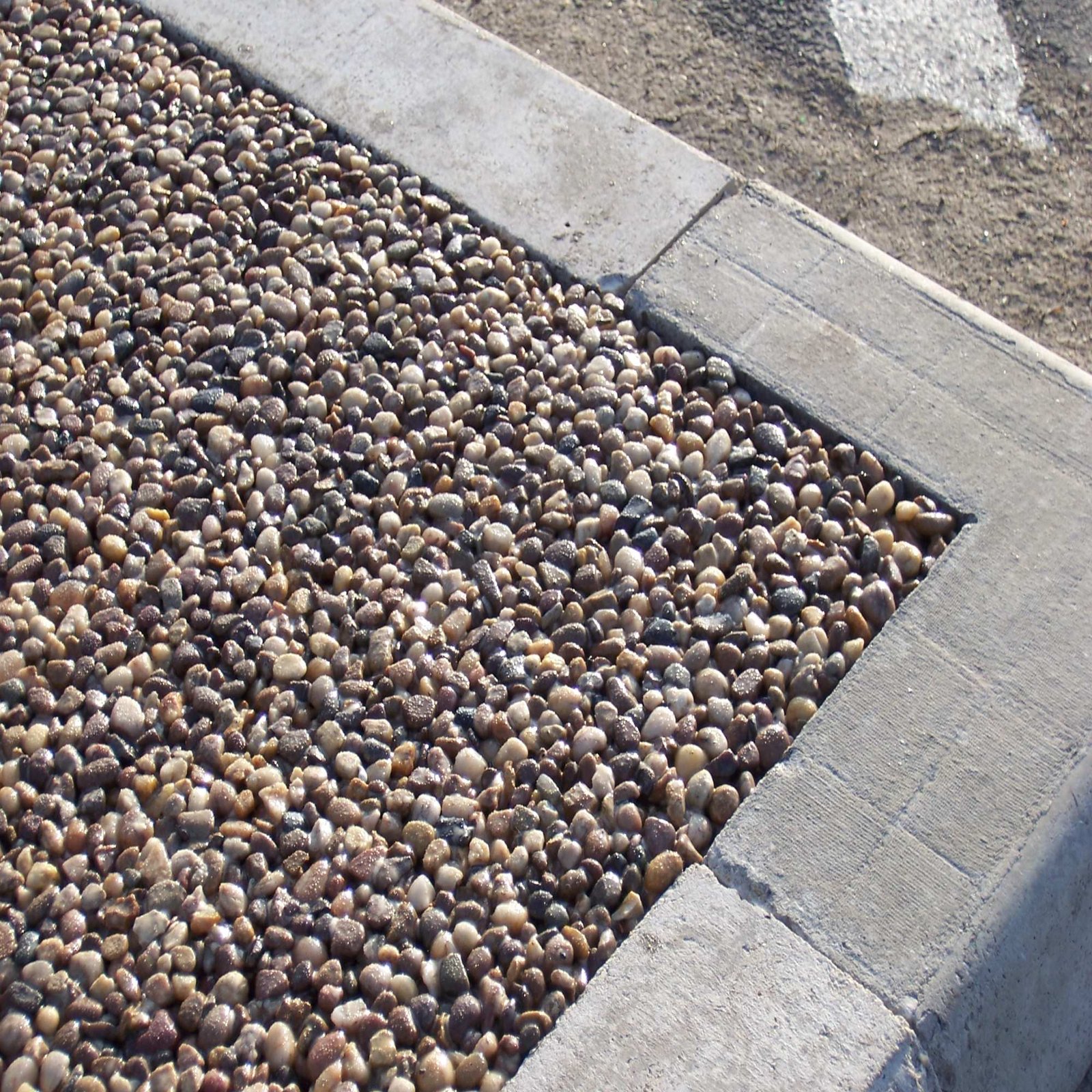 Textured resin bonded gravel surface beside paving edge